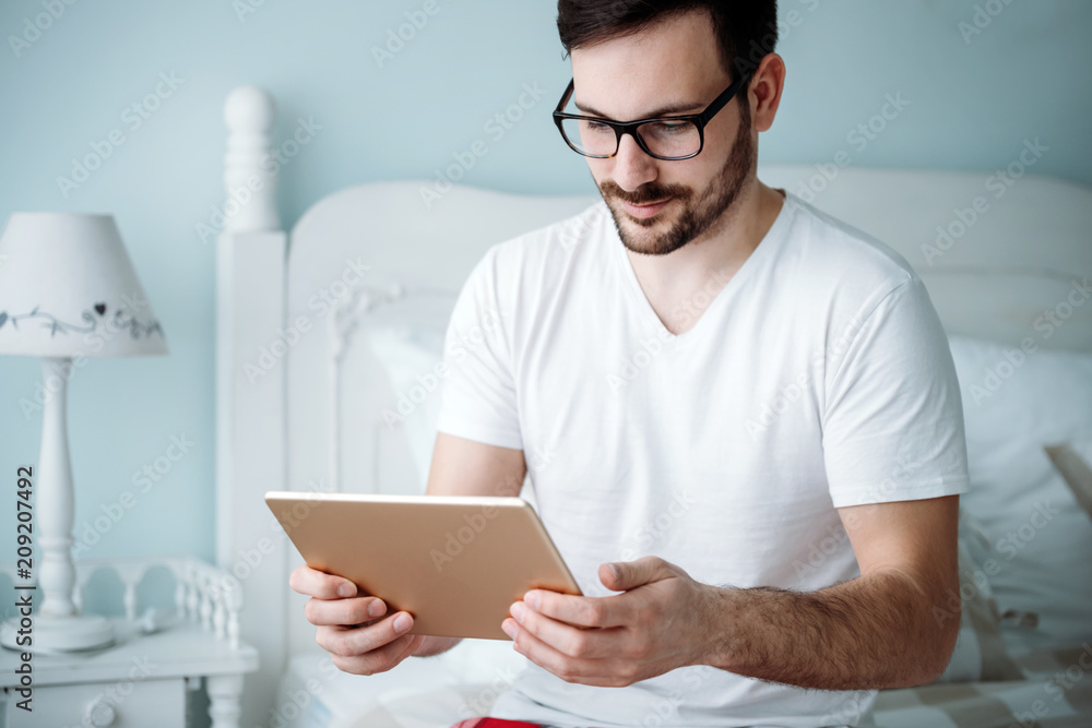 Handsome man using digital tablet in bedroom Handsome man using digital tablet in bedroom