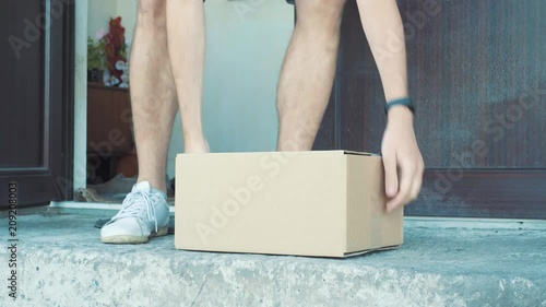 A man picks up a package from outside his front door