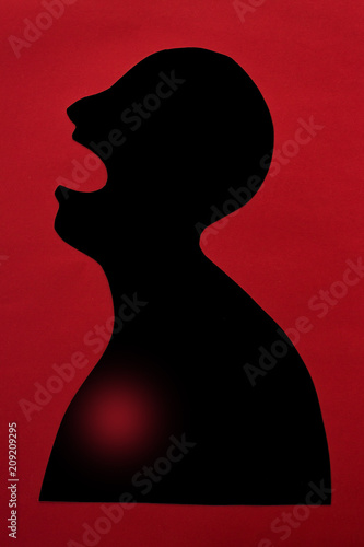concept of human disease diagnosis and pain localization on silhouette - contour of abstract african man with opened mouth and heart failure, isolated on red background, top view, flat lay.