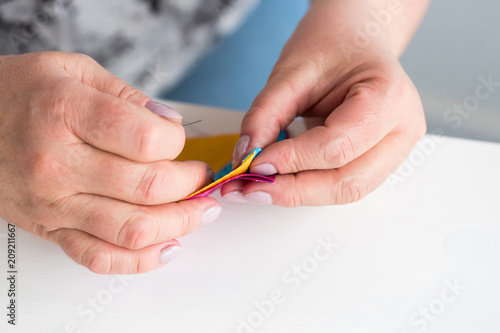 sewing  hobby  handcraft concept. close up of aged female dressmaker with accurate manicure  she is holding colorful patches of fabric and preparing to stitch them together