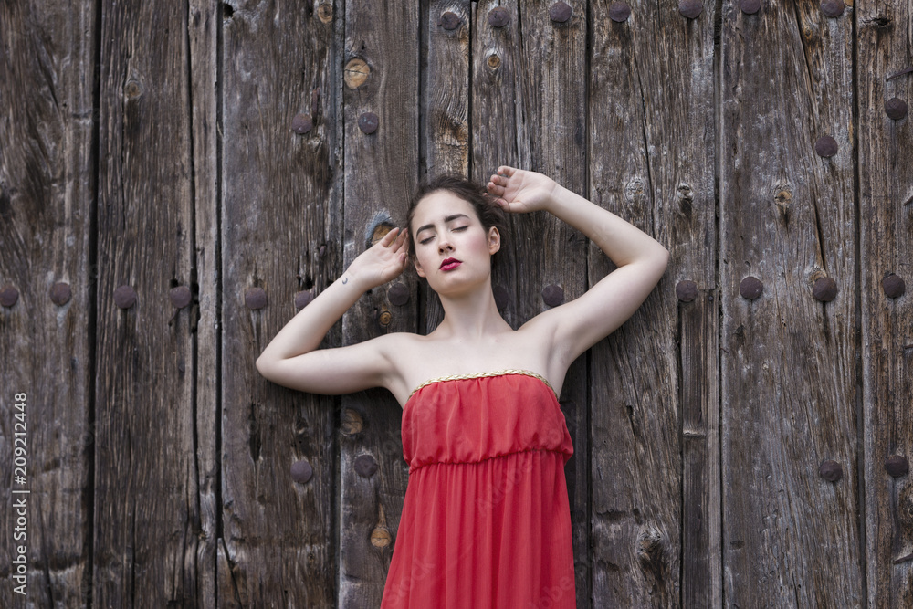 Portrait of a girl in red dress on a wooden door Portrait of a girl in red dress on a wooden door