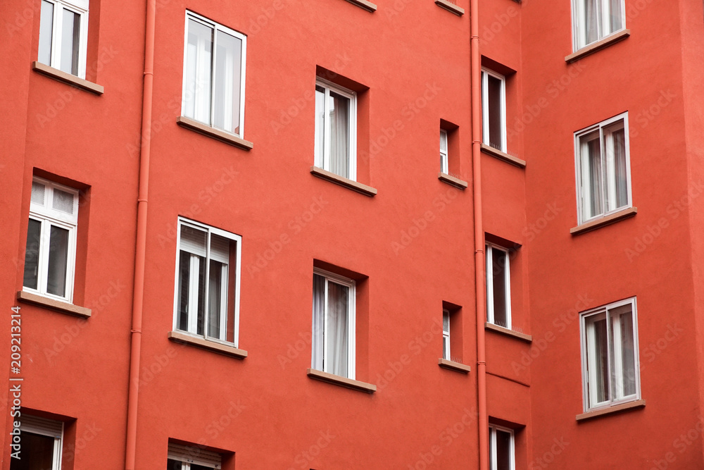 Decorative white window on an old red urban wall .