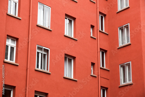 Decorative white window on an old red urban wall .
