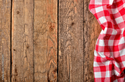 Red checkered tablecloth right frame on vintage wooden table background - view from above