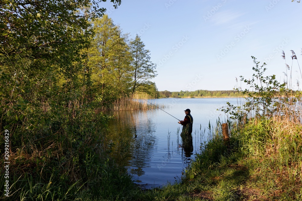 fisherman standing in the lake and catching the fish during sunny day.