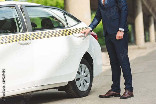 cropped shot of young man in suit opening door of taxi cab © LIGHTFIELD STUDIOS