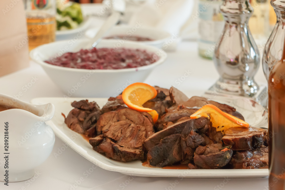 Gefüllte Schweinebraten mit Speckstreifen und Rotkohlsalat auf dem Tisch serviert. Gefüllte Schweinebraten mit Speckstreifen und Rotkohlsalat auf dem Tisch serviert.