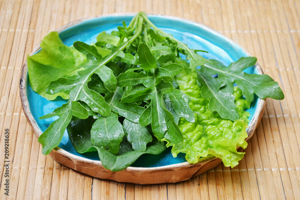 Summer mix of vegetables arugula salad spinach in blue plate on wooden surface Summer mix of vegetables arugula salad spinach in blue plate on wooden surface