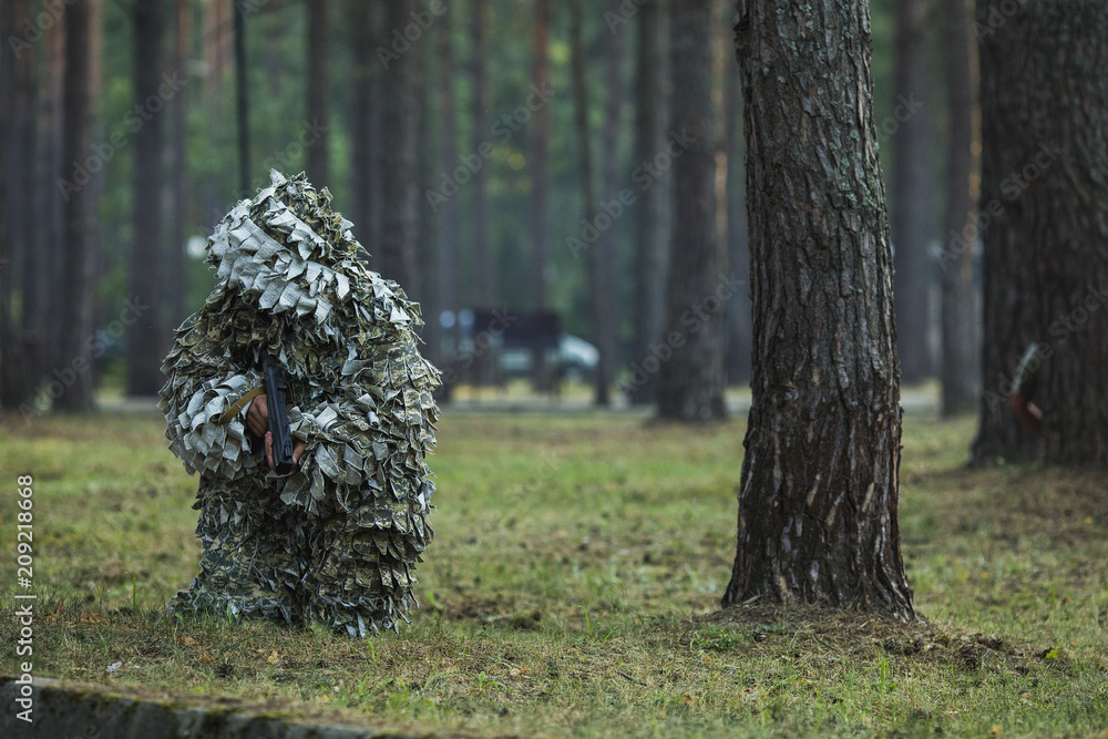the soldier on a position in the wood in a camouflage suit the soldier on a position in the wood in a camouflage suit