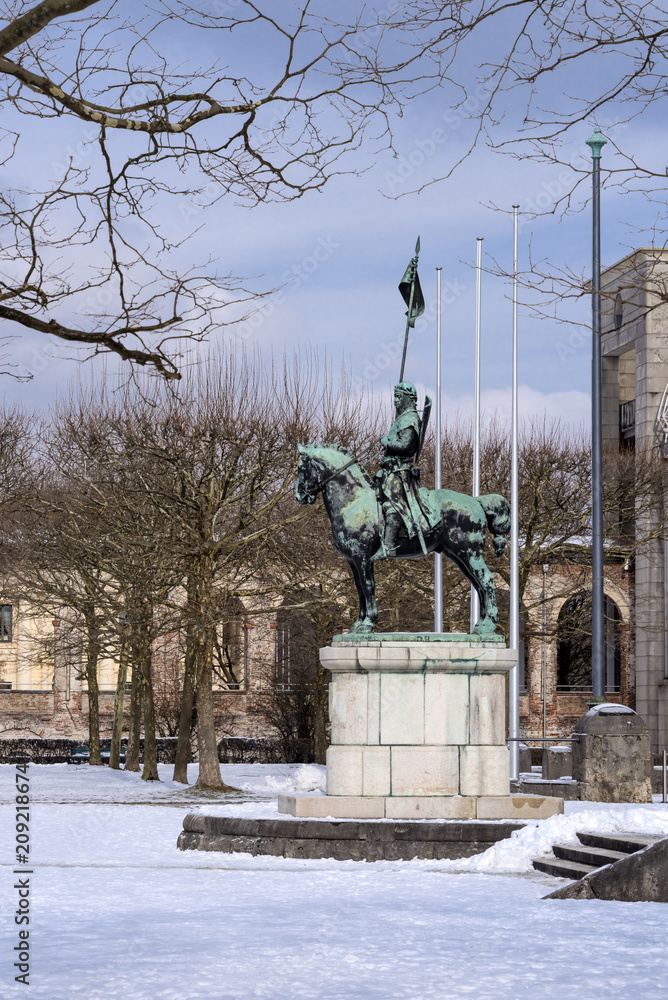 Fototapeta premium Germany, Bavaria, Munich, Hofgarten: Winter scene of War memorial with equestrian statue, white snow, public park in famous Court Garden in the German city center of the Bavarian capital and blue sky.