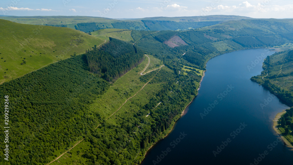 Aerial view of a large reservoir in a deep valley surrounded by green fields (Tal-y-Bont, Wales)