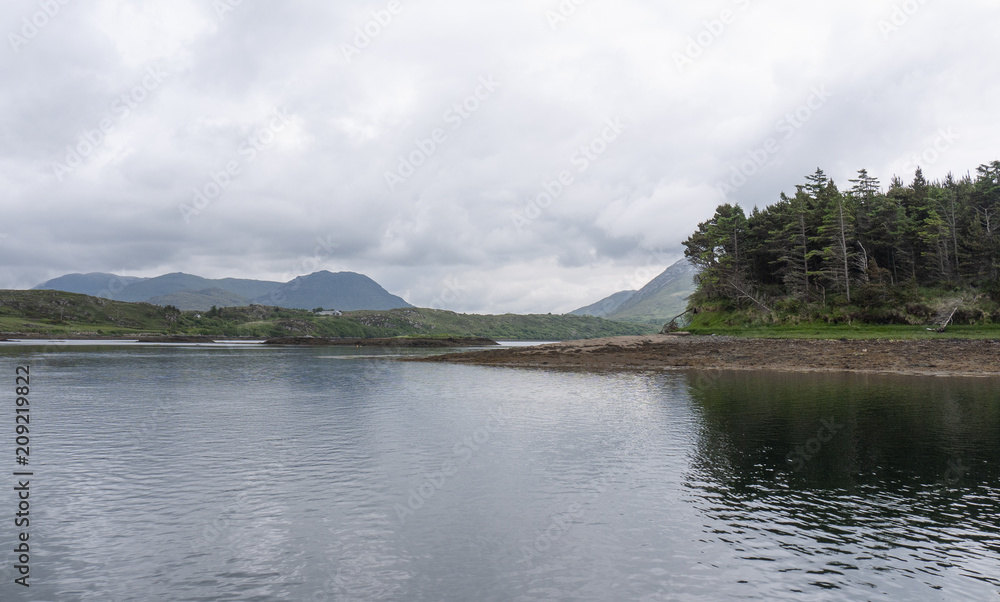 Calm ocean, overcast skies and mountains in Letterfrack, along the Wild Atlantic Way in County Galway Ireland.