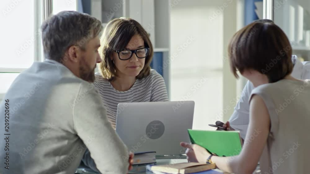 Tracking shot of multiethnic team of businessmen and businesswomen writing in notepads, using laptop and talking at meeting in the office Tracking shot of multiethnic team of businessmen and businesswomen writing in notepads, using laptop and talking at meeting in the office