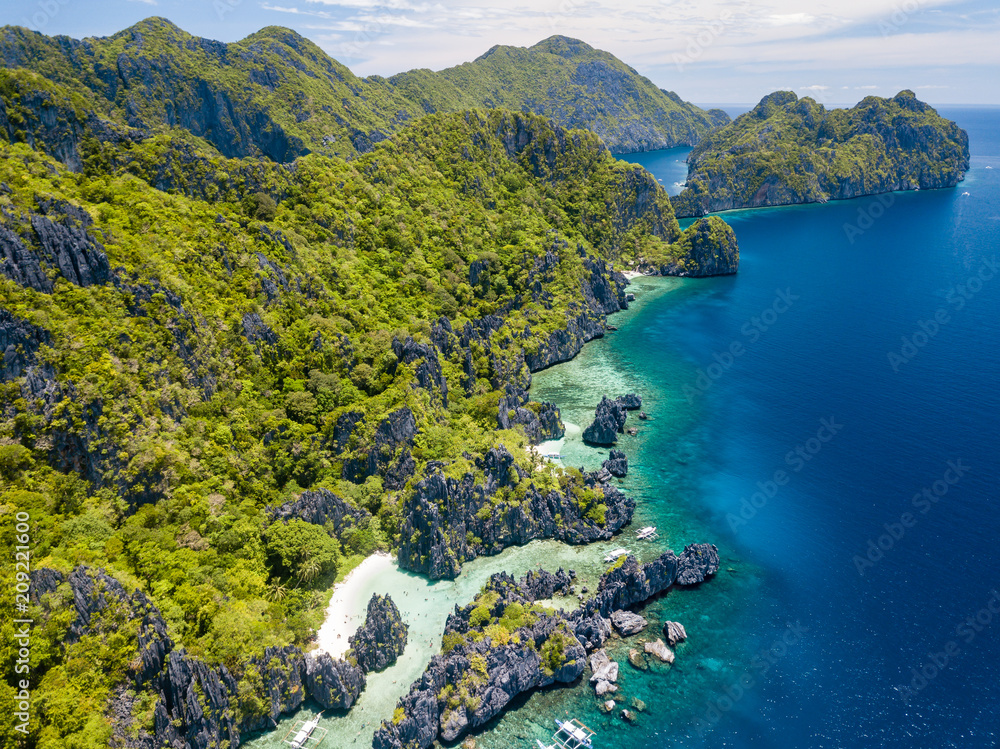 Aerial drone view of spectacular tropical scenery with towering cliffs, jungle and pristine sandy beaches