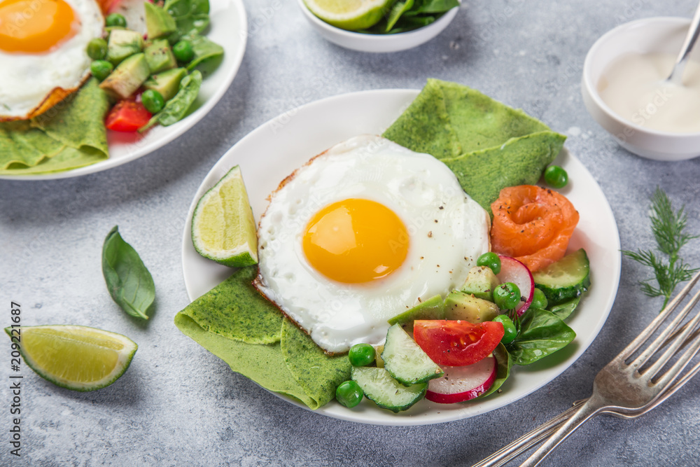 green spinach crepes with fried eggs, smoked salmon and vegetables for breakfast green spinach crepes with fried eggs, smoked salmon and vegetables for breakfast