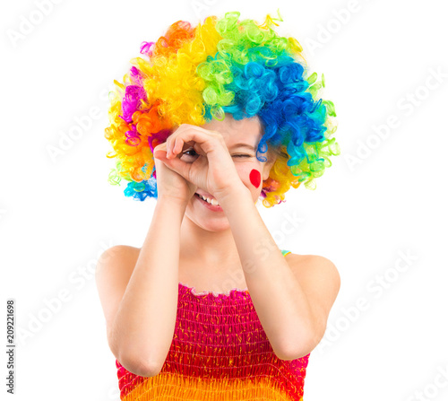 Cute little girl in colourful clown loooking through her hands like binocular  isolated on white backgrond