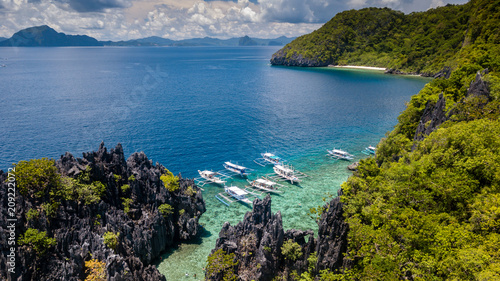 Aerial drone view of traditional boats next to a beautiful tropical lagoon