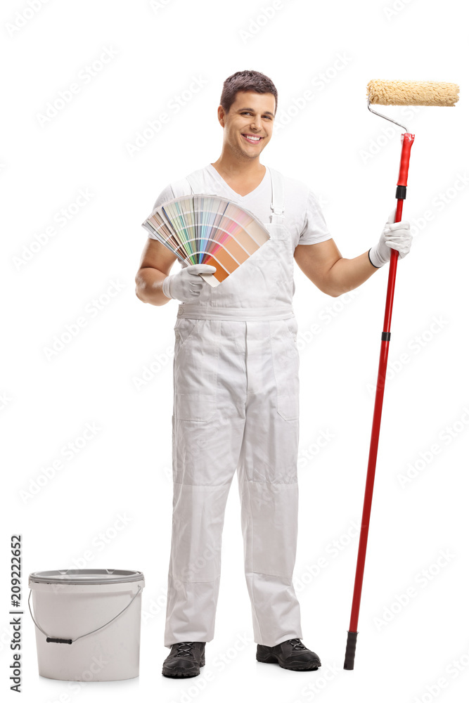Painter with a color swatch and a paint roller standing next to a bucket Painter with a color swatch and a paint roller standing next to a bucket