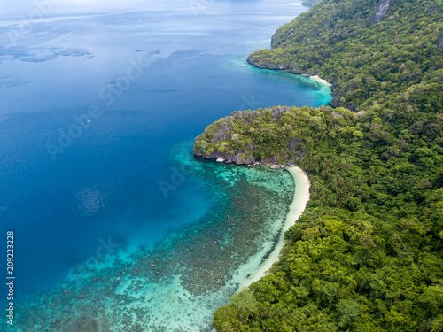 Aerial drone view of a tropical island, surrounding coral reefs, jungle and beaches