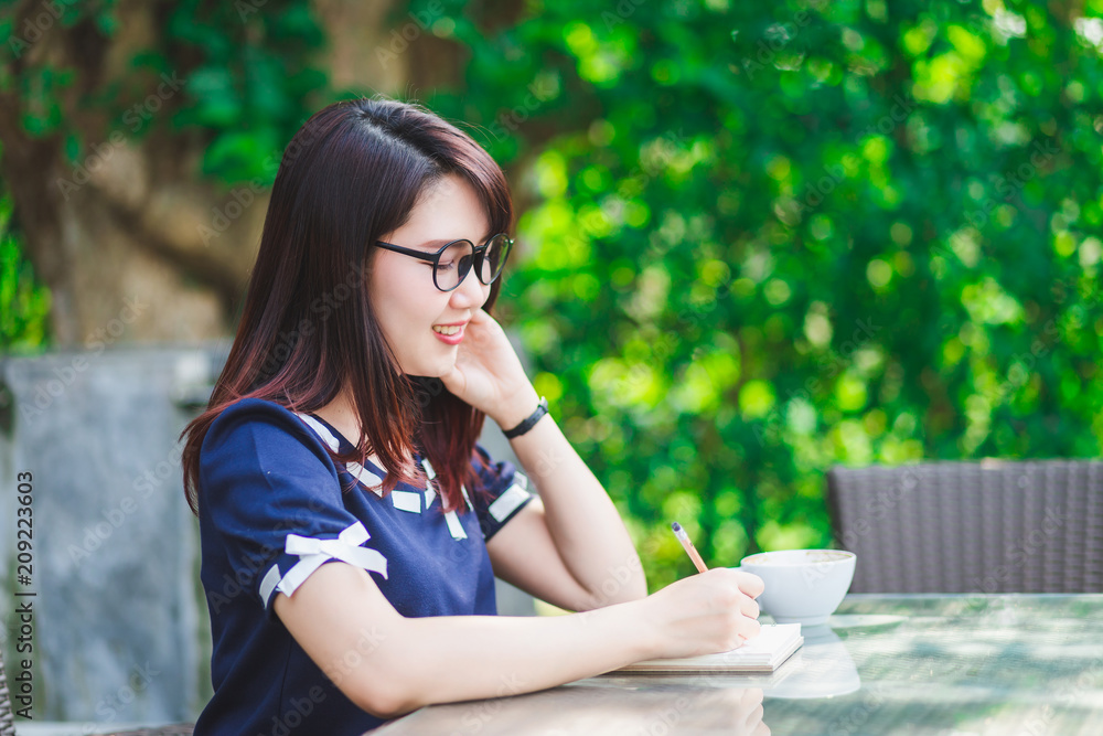 Asian happy young business woman working make a note of something making notes in summer park. Asian happy young business woman working make a note of something making notes in summer park.