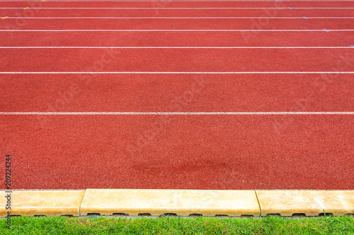White lines of stadium and texture of running racetrack red rubber racetracks in outdoor stadium are 8 track and green grass field,empty athletics stadium with track,football field, soccer field. © Thinapob