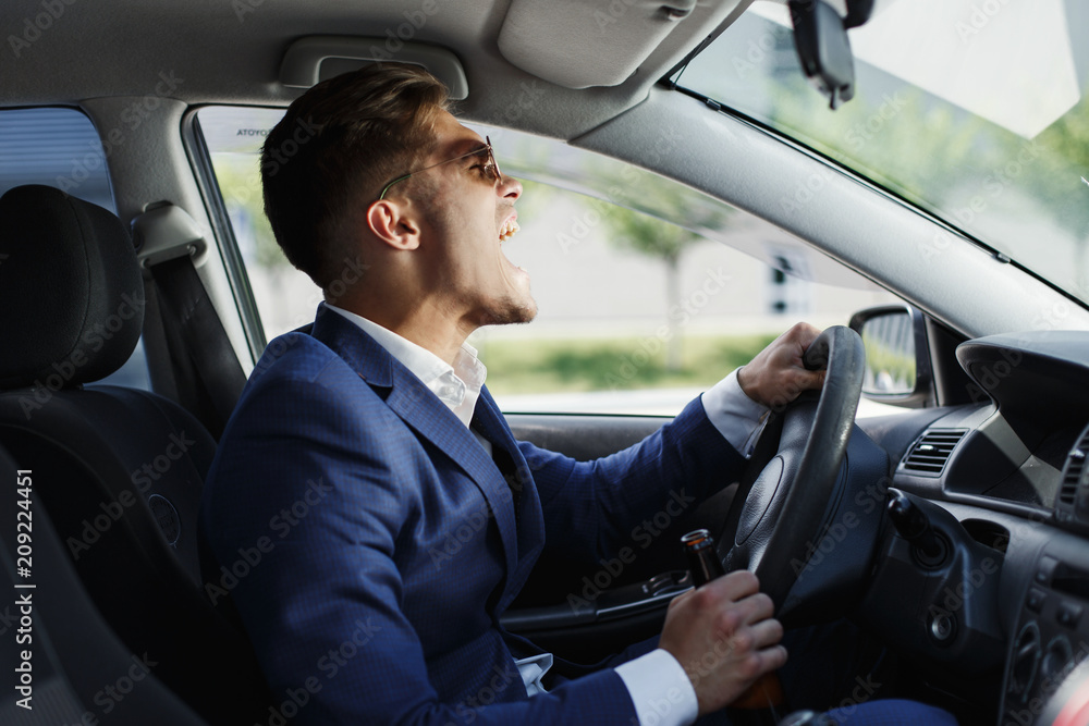 Happy businessman sits shows his emotions sitting at the steering wheel inside the car Happy businessman sits shows his emotions sitting at the steering wheel inside the car