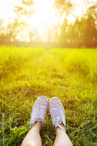 Feet in white sneaker on the grass in the Rice field. Alone travel concept