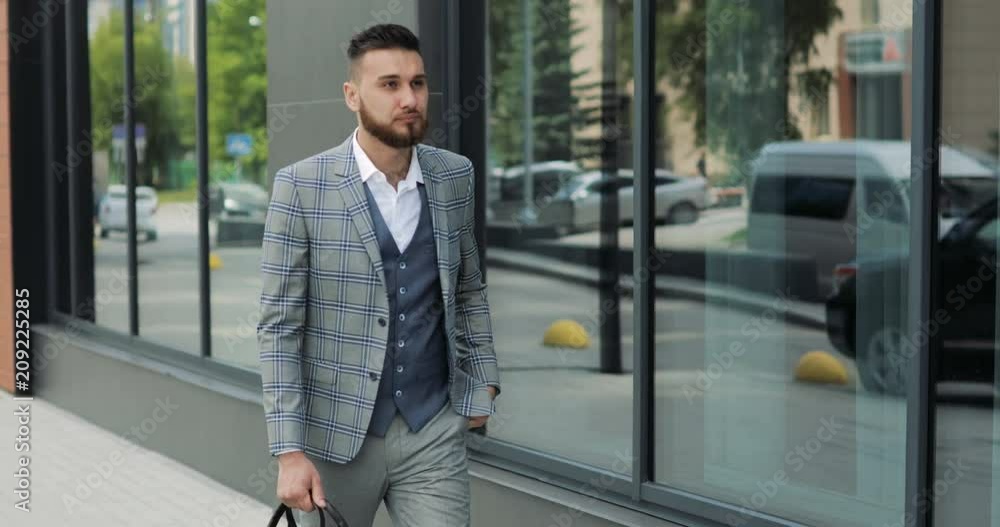 A young handsome businessman student in a suit, comes with a briefcase, at the station, at the airport or business center A young handsome businessman student in a suit, comes with a briefcase, at the station, at the airport or business center
