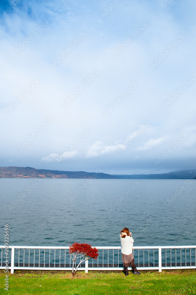 Fototapeta premium Japanese woman standing by lake Toya shore with Nakajima island view, Hokkaido