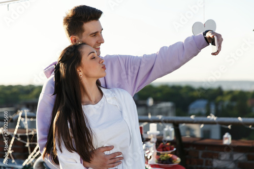 Man takea a selfie with his girlfriend standing on the rooftop