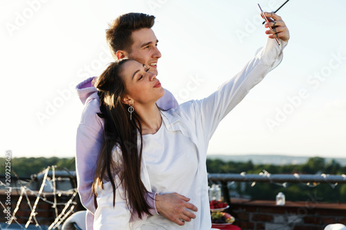 Girl takea a selfie with his boyfriend standing on the rooftop photo