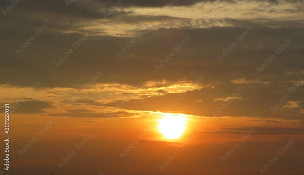 Beautiful golden orange sunset background with dark clouds