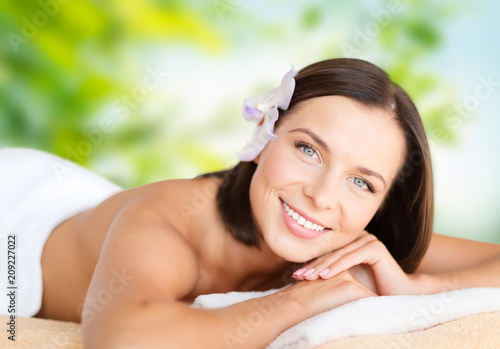 wellness and beauty concept - close up of beautiful woman at spa over green natural background
