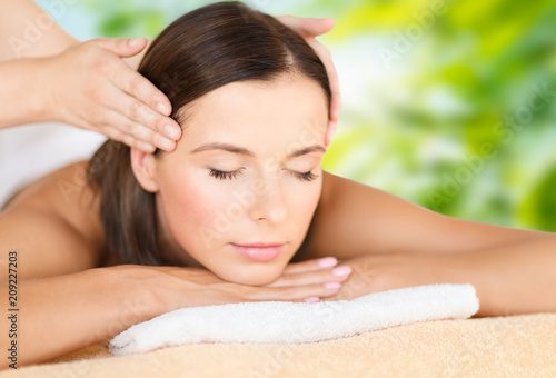 wellness  spa and beauty concept - close up of beautiful woman having head massage over green natural background
