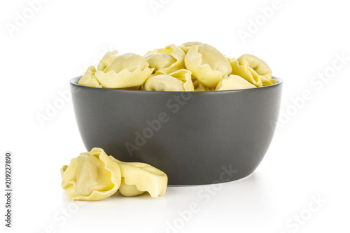 Raw Italian tortellini pasta in a grey ceramic bowl isolated on white background traditional dumplings.