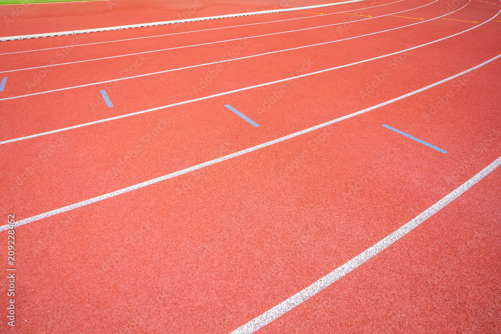 White lines of stadium and texture of running racetrack red rubber racetracks in outdoor stadium are 8 track and green grass field,empty athletics stadium with track.