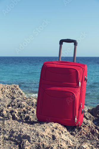 Red suitcase in a rocky coast. Selective focus