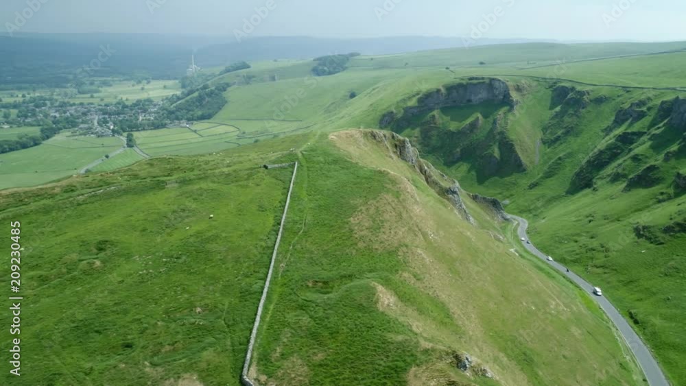 Long winding road between two scenic  Hills on a sunny day with dark clouds in background 1