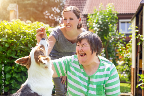 Alternativetherapie mit einem Hund, geistig behinderte Frau und Therapeutin im Garten photo
