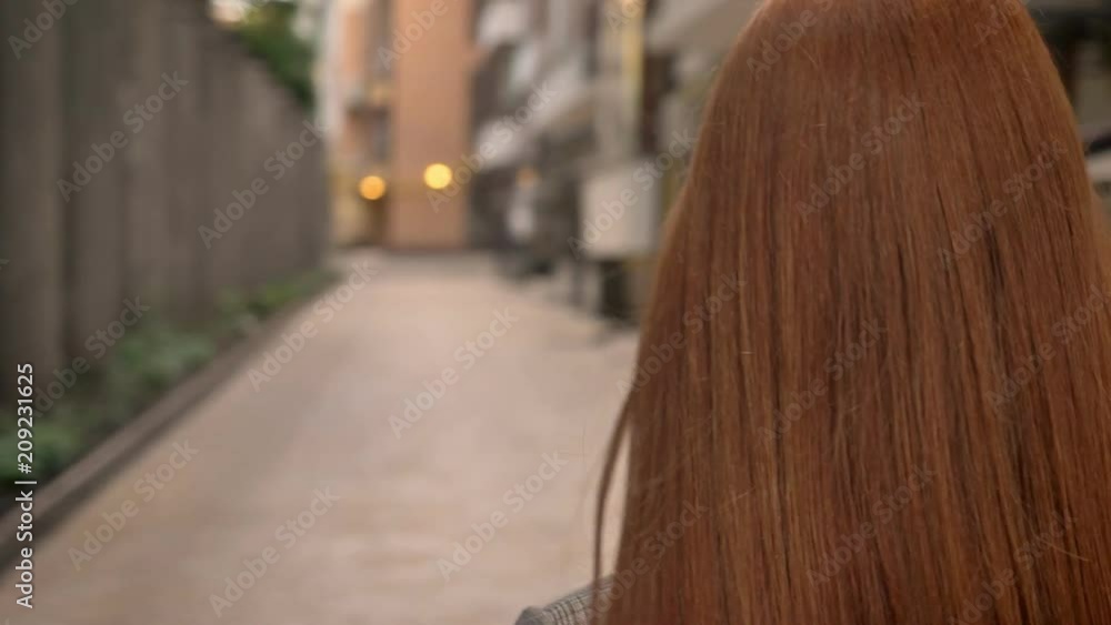 Portrait of young beautiful ginger woman walking on the city street and looking forward, circling view Portrait of young beautiful ginger woman walking on the city street and looking forward, circling view