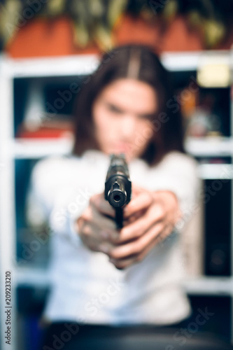 Close up of gun in ladys hands. Close up picture of gun being held by woman dressed in white blouse blurred in background. © Svyatoslav Lypynskyy