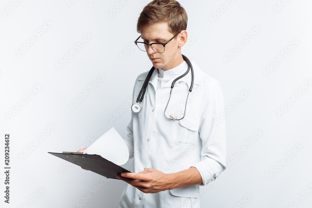 The doctor makes notes in the documents, a young student with a folder in his hands, on a white background The doctor makes notes in the documents, a young student with a folder in his hands, on a white background