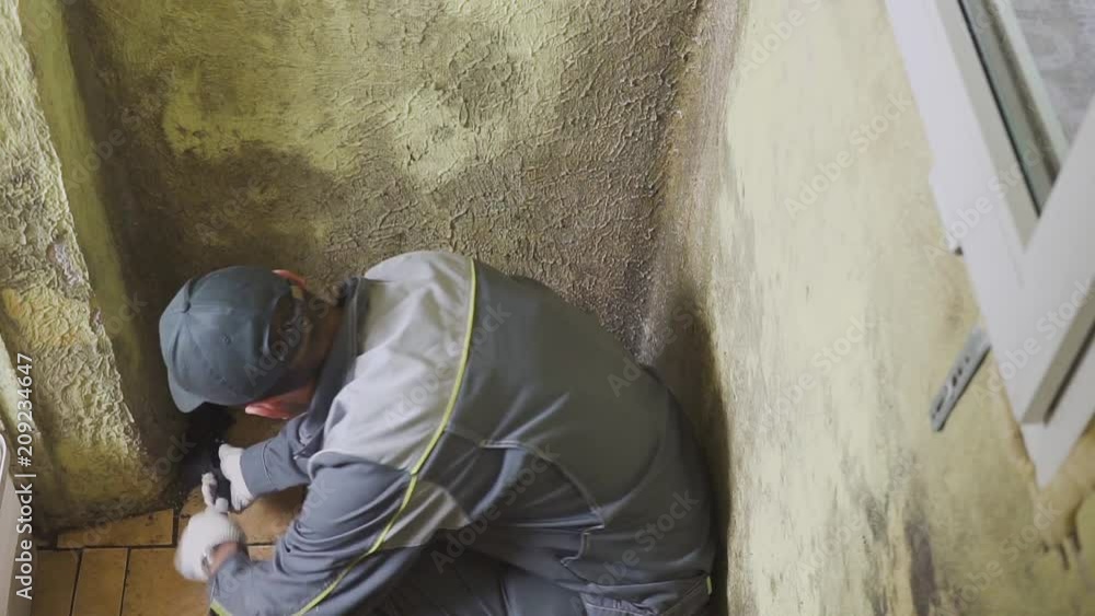 The man cleans the walls of strong dirt with a brush and a rag. The worker washes the corridor walls manually. Mold and dirt. Hard work The man cleans the walls of strong dirt with a brush and a rag. The worker washes the corridor walls manually. Mold and dirt. Hard work