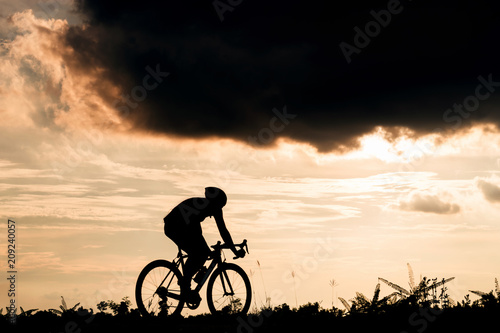 Backside of cyclist ride bicycle on sunset time in public park. Sport and active life concept.