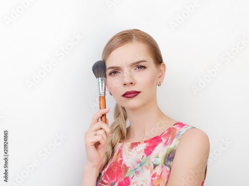 Beauty portrait of young beautiful cheerful young fresh looking make up artist woman with bright trendy make up long blond healthy hair holding cosmetics brush.