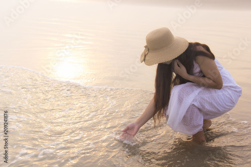 Beautiful woman in white maxi dress on the beach in light of evening