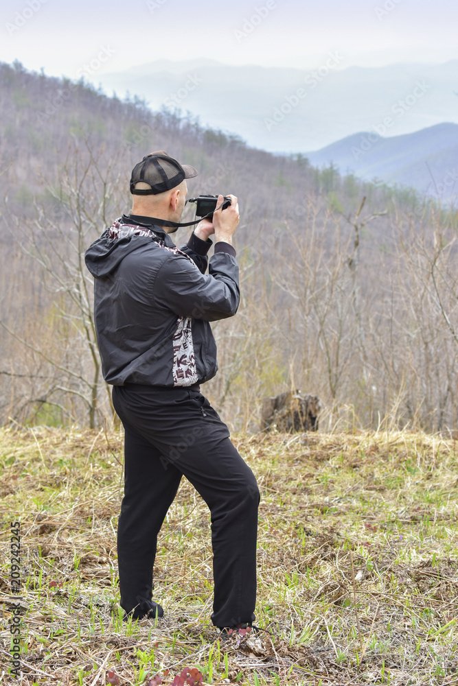 Young man shooting pictures of spring landscape in the mountains of Sikhote Alin Young man shooting pictures of spring landscape in the mountains of Sikhote Alin