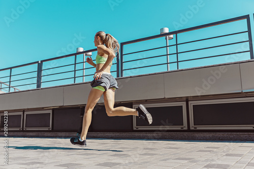 Pretty sporty woman jogging at city