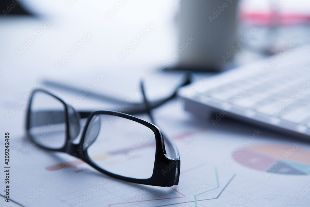 business, objects and statistics concept - close up of eyeglasses and files on office table business, objects and statistics concept - close up of eyeglasses and files on office table