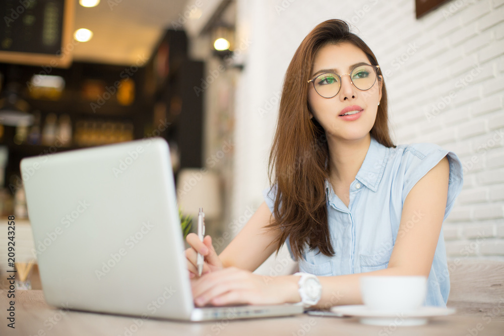 Image of happy woman using laptop while sitting at cafe.woman sitting in a coffee shop and working on laptop. Image of happy woman using laptop while sitting at cafe.woman sitting in a coffee shop and working on laptop.